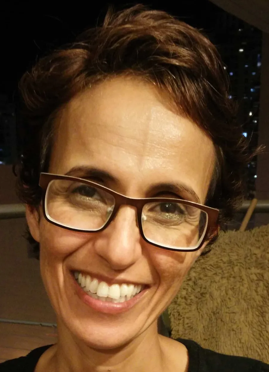 איריס כץ מחייכת, משקפיים ושיער קצר